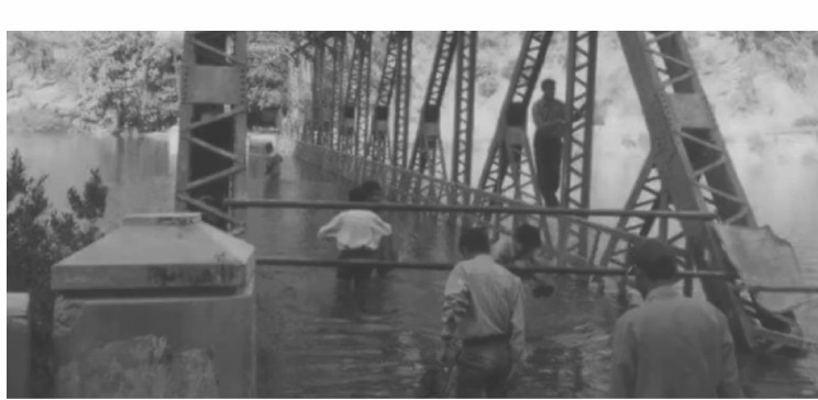 Archive photograph of a bridge partly under water as construction fills the valley.